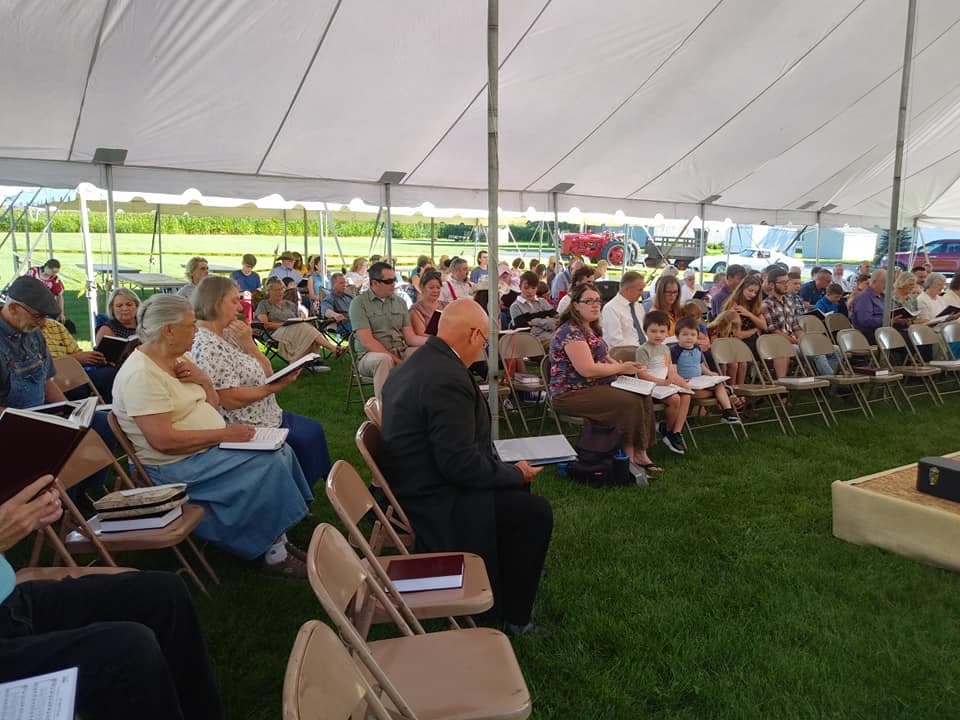 The congregation of Blissfield Baptist Church at an outdoor service, hymnals in hand